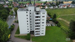 Modernisiertes Hochhaus mit weißen Fassadenplatten und Balkonen