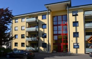 Modernes Wohnhaus mit roten Fassadendetails und Balkonen