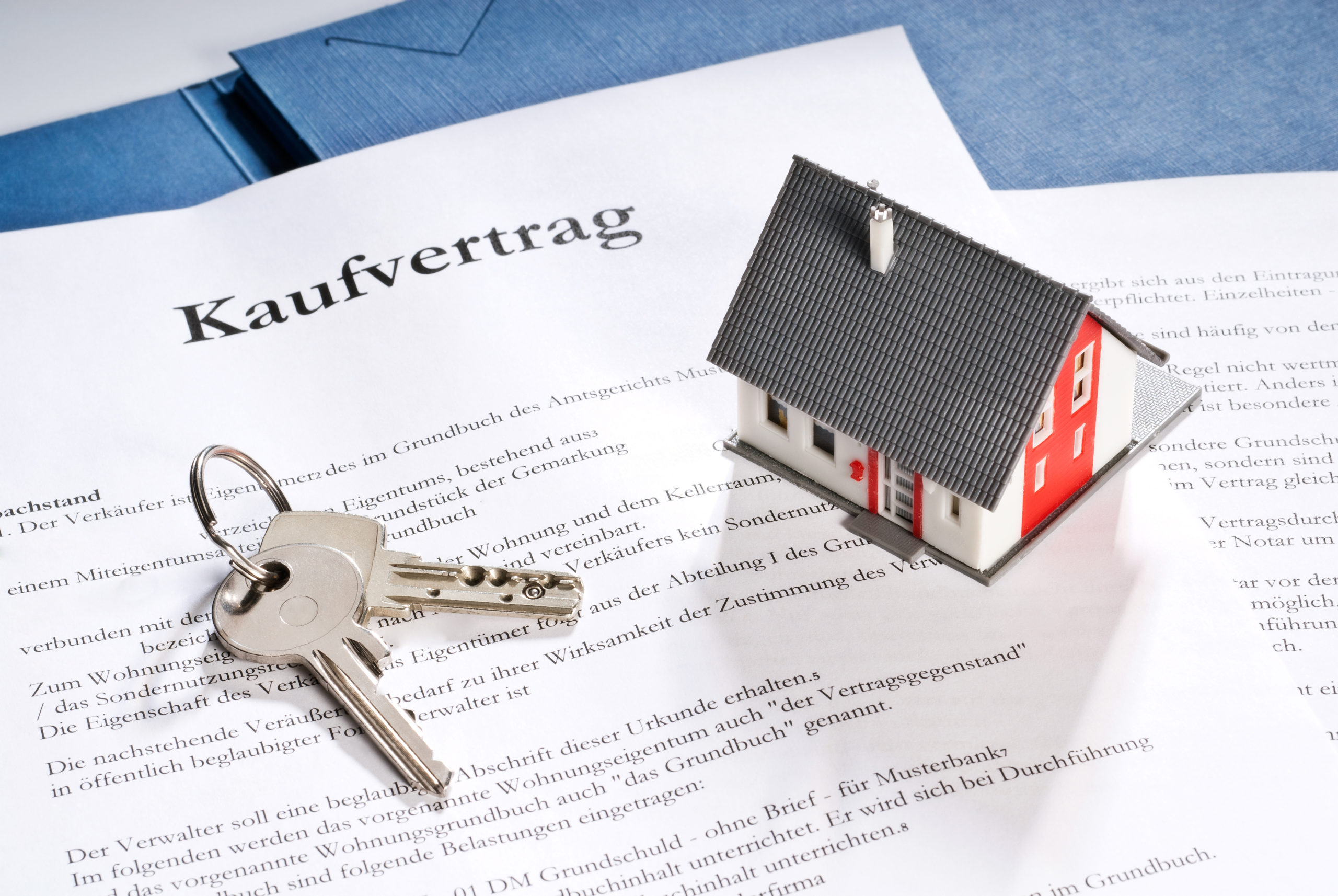 Immobilienkaufvertrag mit Modellhaus und Schlüssel